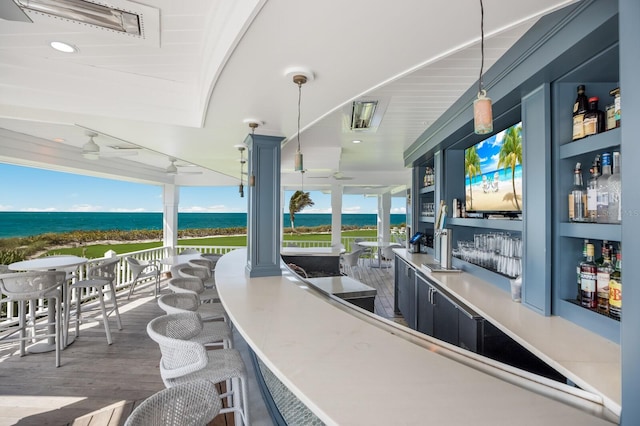 view of patio / terrace featuring an outdoor bar, a water view, and ceiling fan