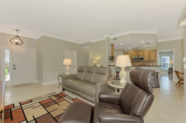 tiled living room featuring crown molding and a chandelier