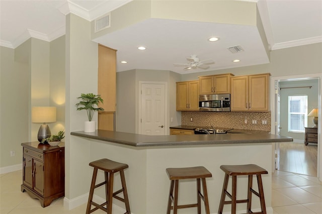 kitchen featuring kitchen peninsula, ceiling fan, a breakfast bar area, and light tile patterned flooring