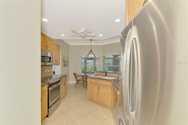 kitchen with appliances with stainless steel finishes, tasteful backsplash, ceiling fan with notable chandelier, sink, and pendant lighting