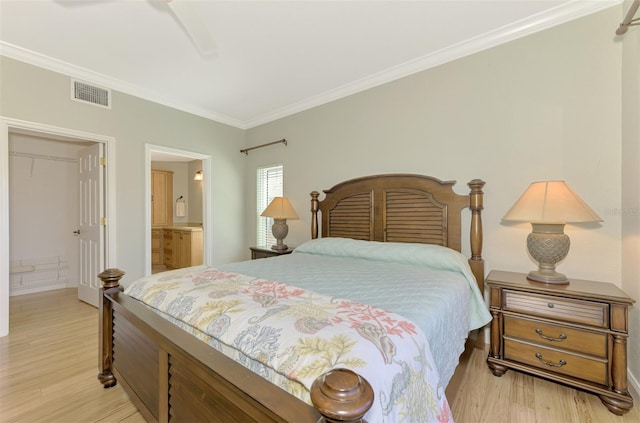 bedroom featuring ensuite bathroom, ceiling fan, light wood-type flooring, and ornamental molding