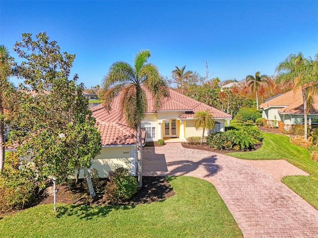 mediterranean / spanish house with a garage and a front lawn