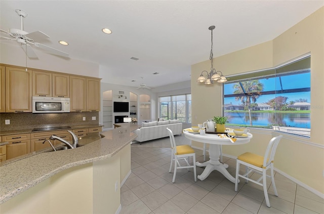 kitchen featuring decorative backsplash, light stone counters, pendant lighting, a notable chandelier, and sink