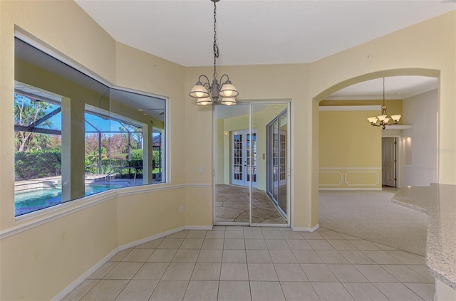 carpeted spare room with a notable chandelier and ornamental molding