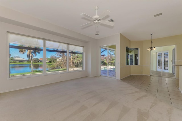 empty room featuring light colored carpet, ceiling fan with notable chandelier, and a water view