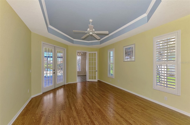 spare room with french doors, a raised ceiling, a wealth of natural light, and hardwood / wood-style floors