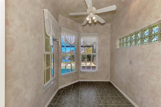 unfurnished room featuring ceiling fan and dark tile patterned floors