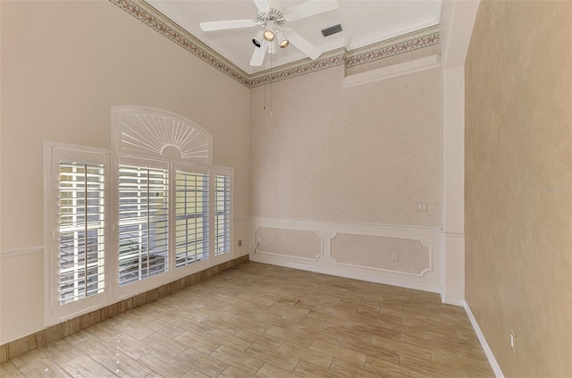 spare room featuring light hardwood / wood-style floors, crown molding, and a towering ceiling