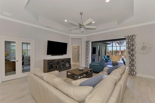 living room with a wealth of natural light, a tray ceiling, and light hardwood / wood-style floors