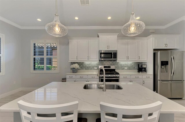 kitchen with white cabinetry, light stone countertops, ornamental molding, sink, and stainless steel appliances