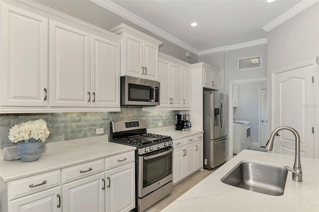 kitchen featuring sink, separate washer and dryer, backsplash, stainless steel appliances, and white cabinets