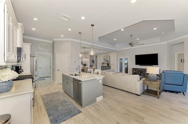 kitchen featuring appliances with stainless steel finishes, sink, an island with sink, decorative light fixtures, and white cabinets