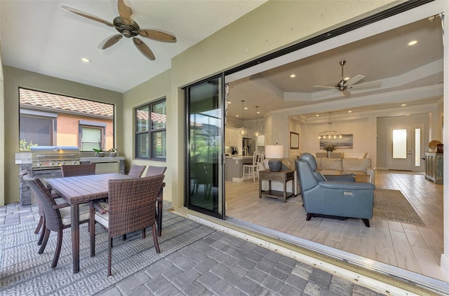 sunroom / solarium featuring a tray ceiling and ceiling fan with notable chandelier