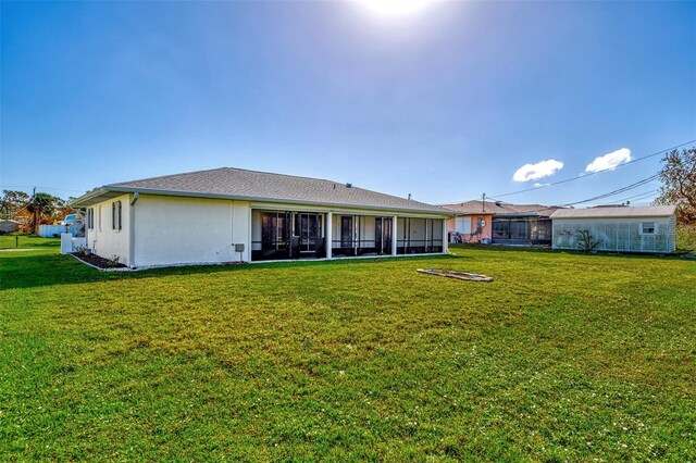 rear view of house with a yard and a sunroom