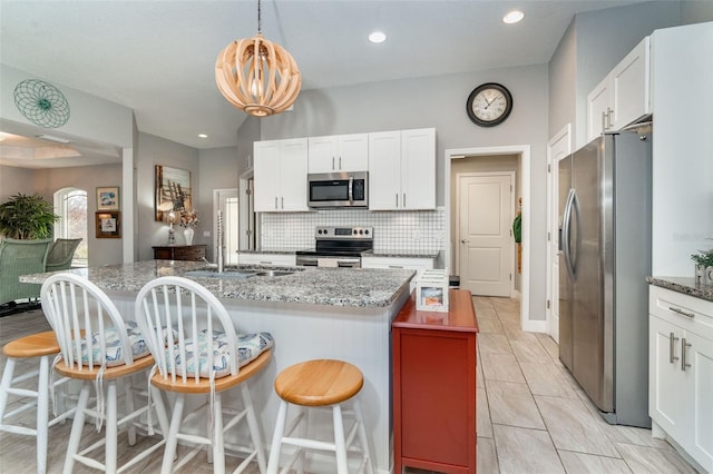 kitchen with a kitchen breakfast bar, white cabinets, stainless steel appliances, and stone countertops