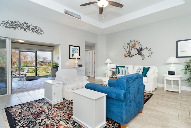 living room featuring ceiling fan and a tray ceiling