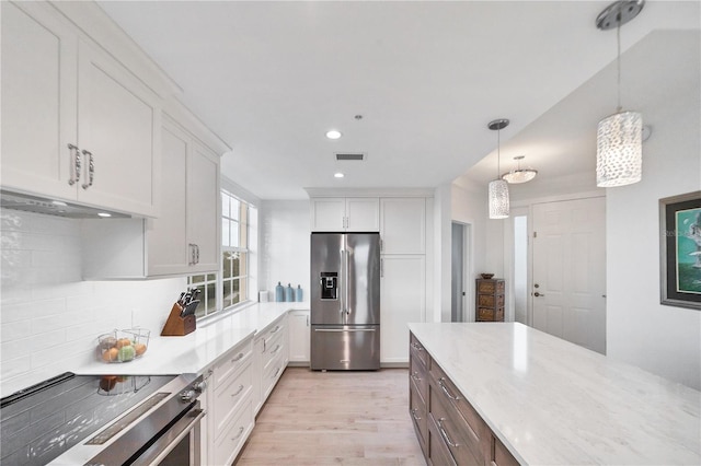 kitchen featuring appliances with stainless steel finishes, pendant lighting, white cabinets, decorative backsplash, and light hardwood / wood-style flooring