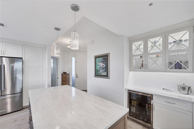 kitchen with high end fridge, hanging light fixtures, white cabinetry, vaulted ceiling, and wine cooler