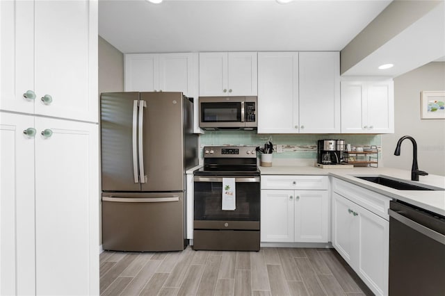 kitchen with backsplash, sink, appliances with stainless steel finishes, and white cabinets