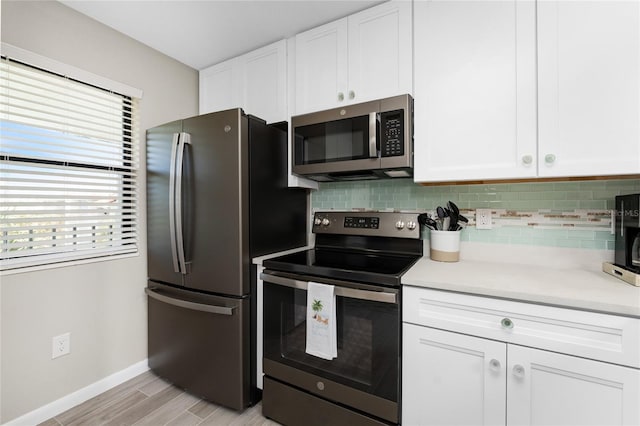 kitchen featuring light hardwood / wood-style floors, appliances with stainless steel finishes, white cabinets, and tasteful backsplash