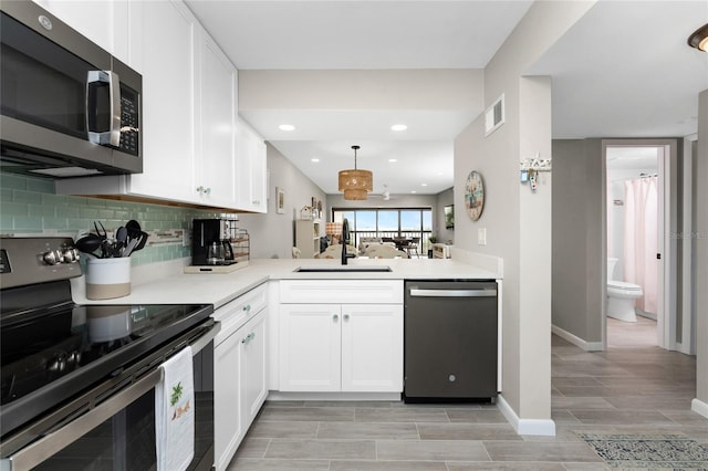 kitchen with sink, white cabinetry, kitchen peninsula, and stainless steel appliances