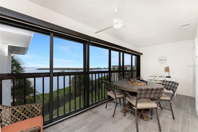 sunroom / solarium featuring a water view and ceiling fan