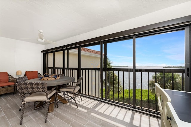 sunroom / solarium featuring a water view and ceiling fan