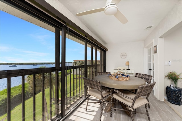 sunroom with a water view and ceiling fan