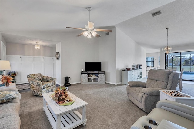 carpeted living room featuring ceiling fan with notable chandelier and lofted ceiling