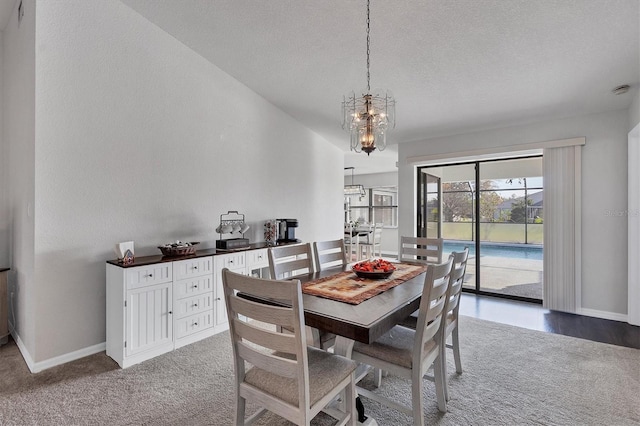 dining room with carpet, a textured ceiling, and an inviting chandelier