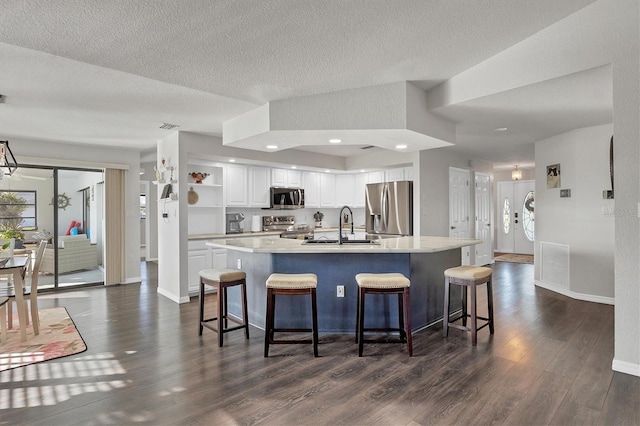 kitchen featuring a breakfast bar, a center island with sink, sink, white cabinetry, and stainless steel appliances