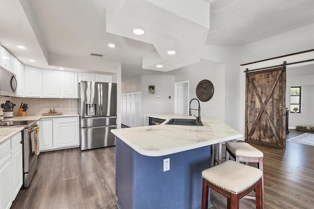 kitchen featuring sink, a barn door, a textured ceiling, white cabinetry, and stainless steel appliances