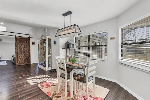 dining space featuring a barn door, dark hardwood / wood-style flooring, and a notable chandelier