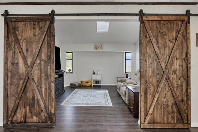 unfurnished living room with a barn door and dark wood-type flooring