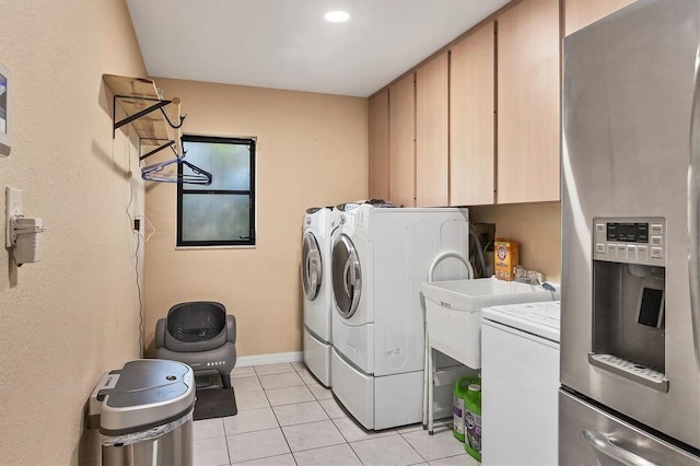 laundry area featuring light tile patterned flooring, cabinets, and separate washer and dryer