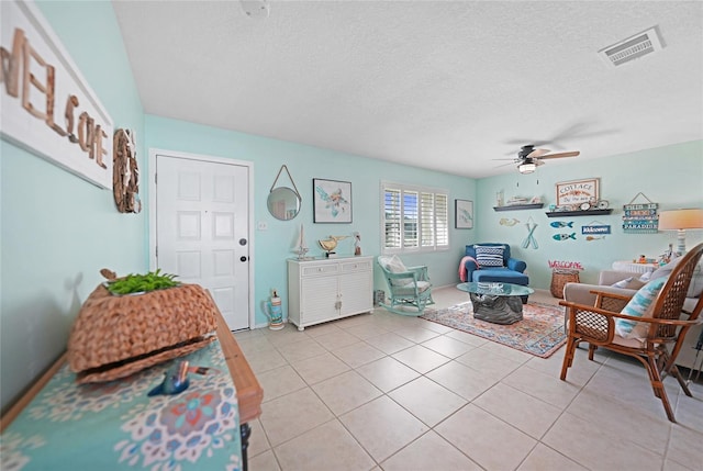 interior space with ceiling fan, a textured ceiling, and light tile patterned floors