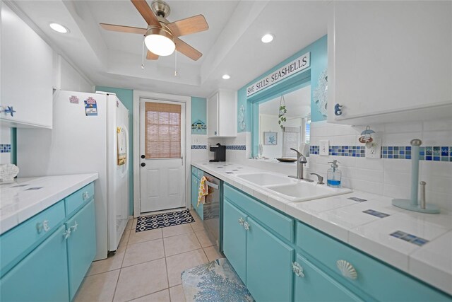 kitchen with decorative backsplash, sink, white cabinets, dishwasher, and a tray ceiling