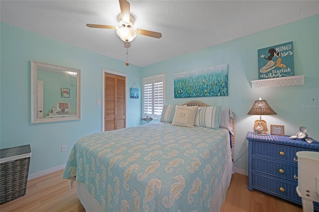 bedroom featuring a textured ceiling, light hardwood / wood-style floors, ceiling fan, and a closet