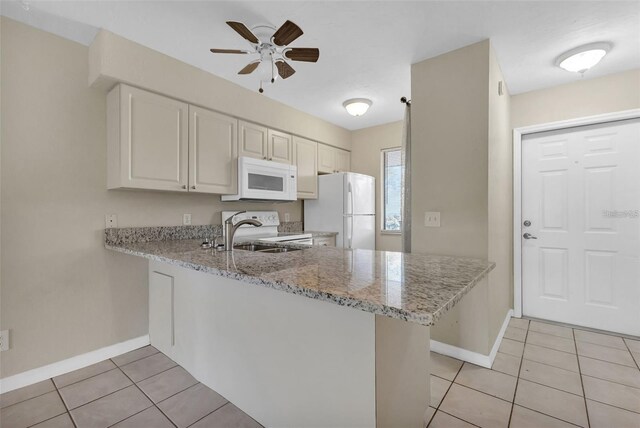 kitchen with white appliances, light stone countertops, light tile patterned flooring, kitchen peninsula, and white cabinetry