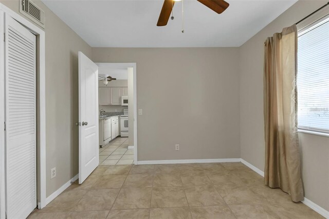 interior space with a closet, ceiling fan, multiple windows, and light tile patterned floors