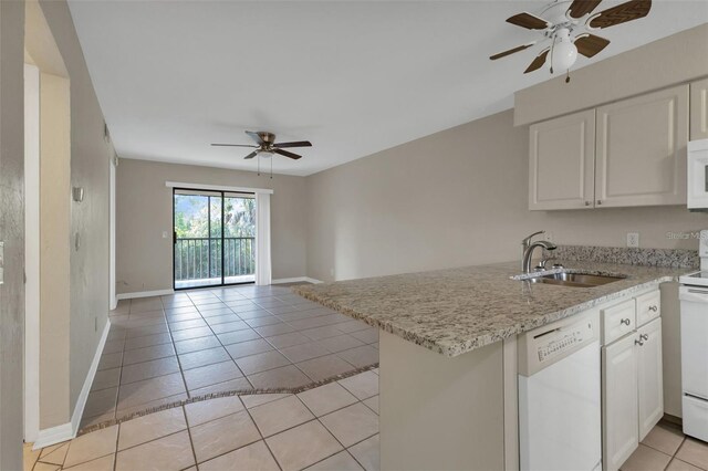 kitchen with white appliances, sink, kitchen peninsula, white cabinetry, and light tile patterned floors