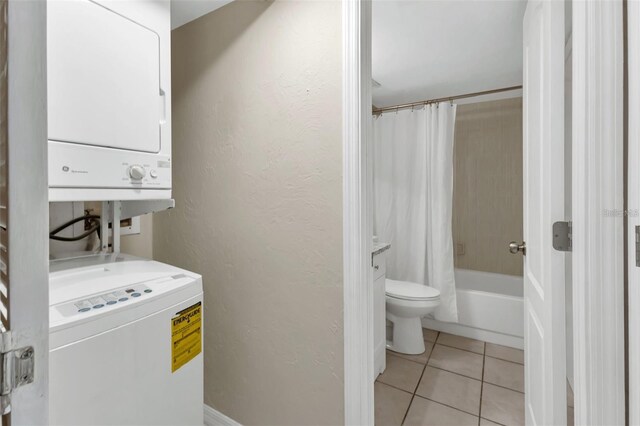 laundry room featuring stacked washer / drying machine and light tile patterned flooring