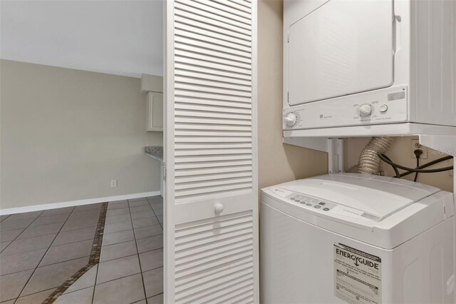 laundry area with stacked washer / dryer and light tile patterned floors