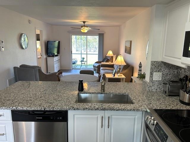 kitchen with stainless steel dishwasher, ceiling fan, white cabinets, and tasteful backsplash