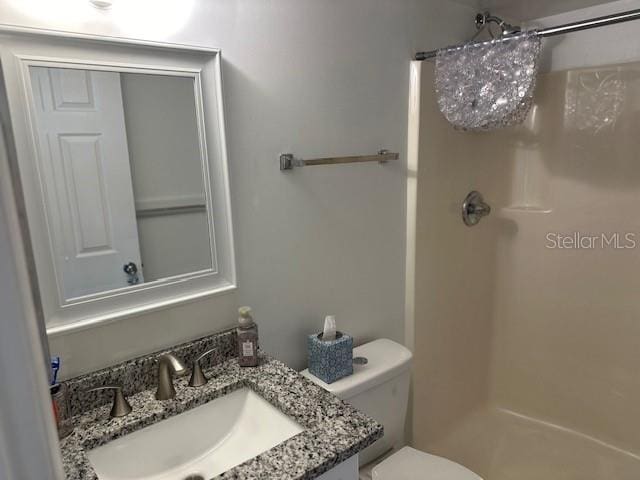 bathroom with a shower, vanity, and toilet