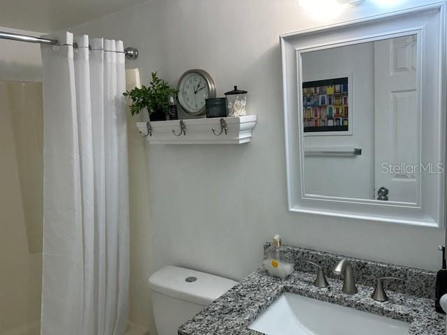 bathroom with vanity, curtained shower, and toilet