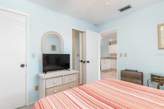 carpeted bedroom with a textured ceiling and ensuite bathroom