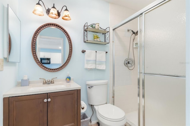 bathroom with toilet, an enclosed shower, and vanity