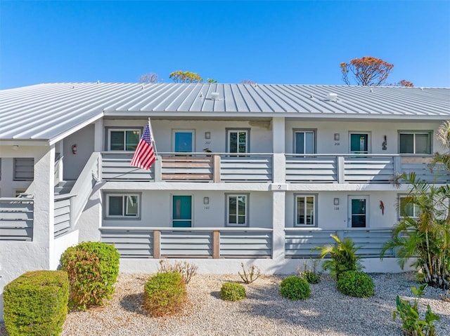 view of front of home with metal roof, a standing seam roof, a balcony, and stucco siding