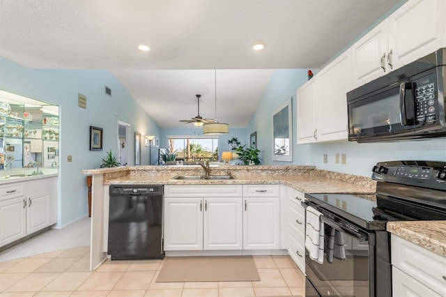 kitchen featuring lofted ceiling, a peninsula, black appliances, white cabinetry, and a sink